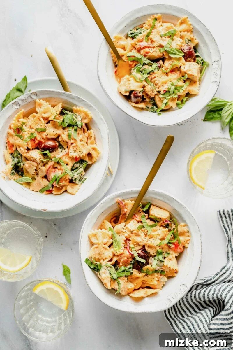 Dreamy Boursin Pasta Delight 2 Three white bowls are filled with cheesy bowtie pasta, garnished with fresh basil.