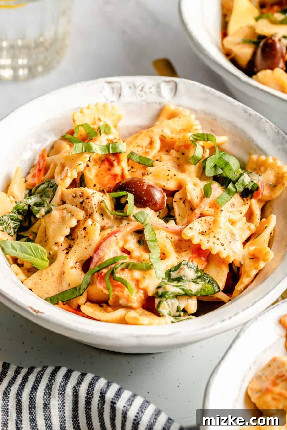 Dreamy Boursin Pasta Delight 3 Close-up of a bowl of creamy Boursin tomato pasta topped with fresh green basil leaves.