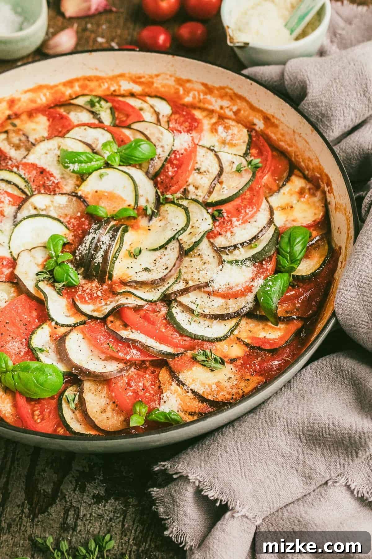 Ratatouille in round baking dish, garnished with fresh basil leaves
