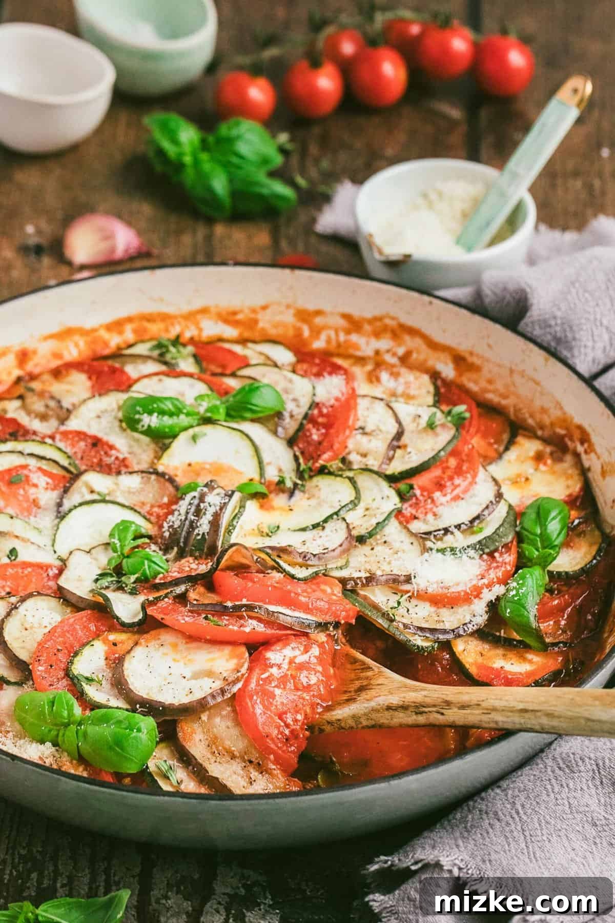 Ratatouille in round baking dish with a wooden spoon, ready to serve