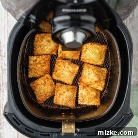 browned and crispy air fried ravioli in the basket of an air fryer