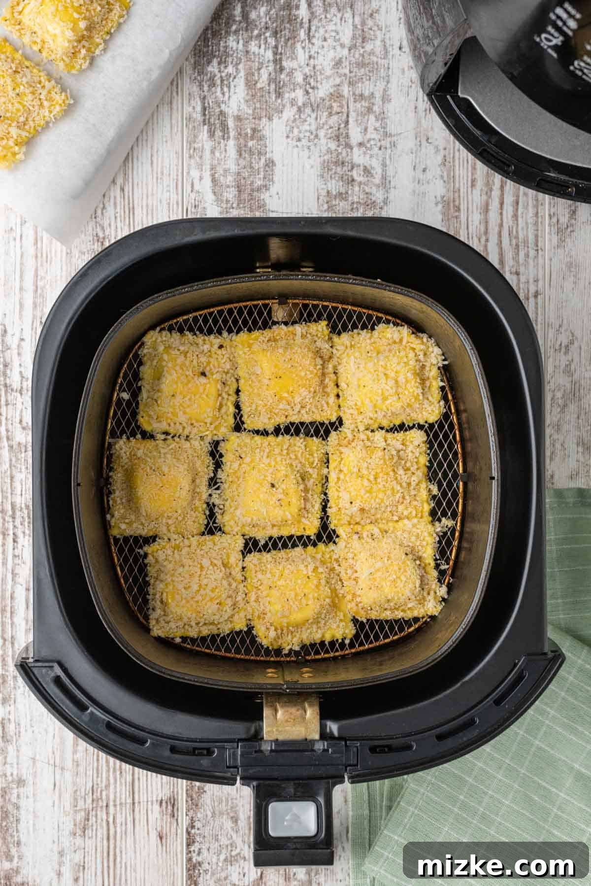 Panko-coated ravioli inside an air fryer basket, arranged in a single layer