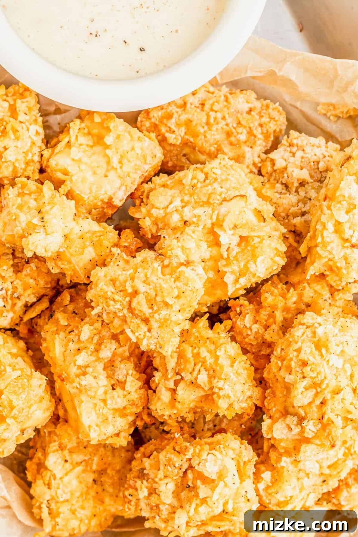 Crispy Tofu Poppers 4 A generous pile of golden-brown, crispy popcorn tofu, artfully arranged on a serving plate alongside a small bowl of dipping sauce.