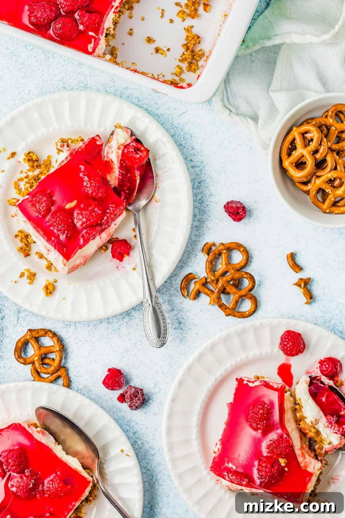 Raspberry Pretzel Delight 6 An overhead view of multiple slices of Raspberry Pretzel Salad on individual plates, ready for serving.