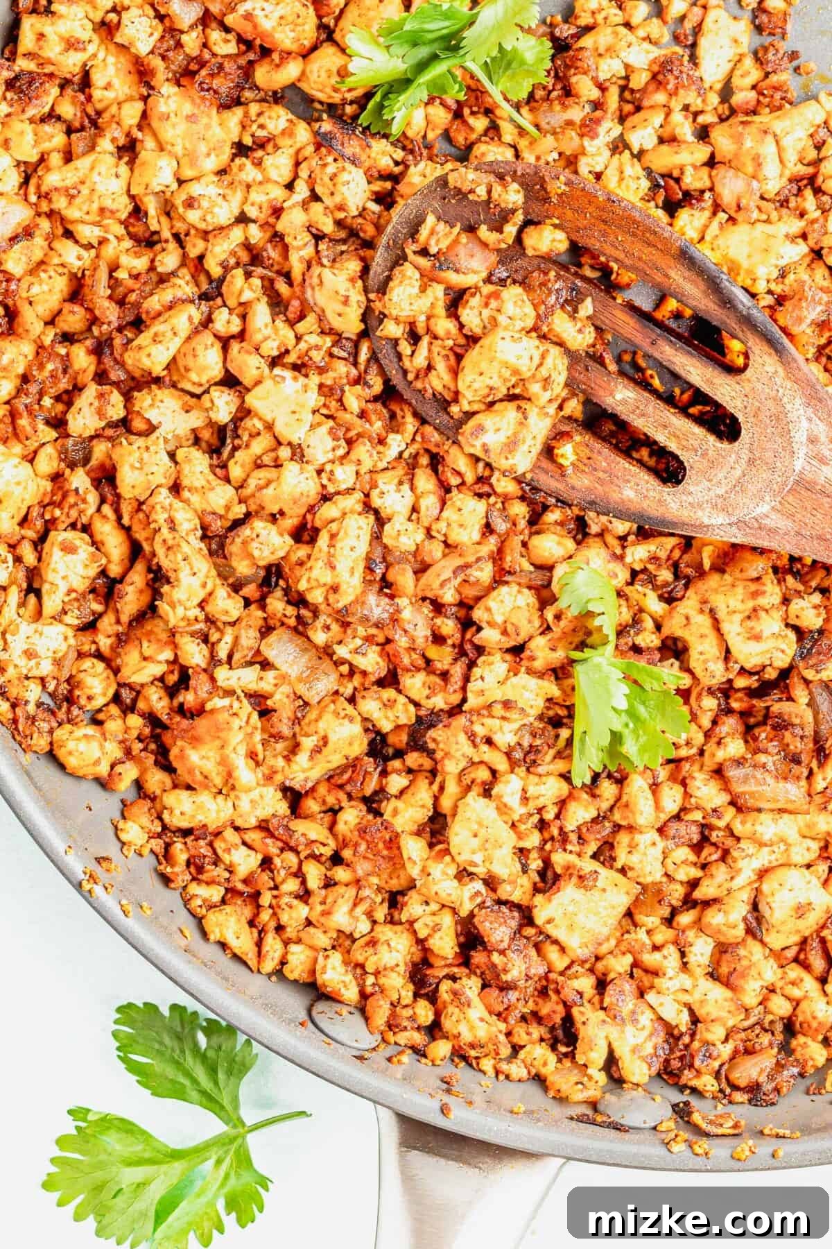 Spicy Tofu Chorizo 2 Sizzling tofu chorizo in a skillet with a wooden slotted spoon, ready to serve.