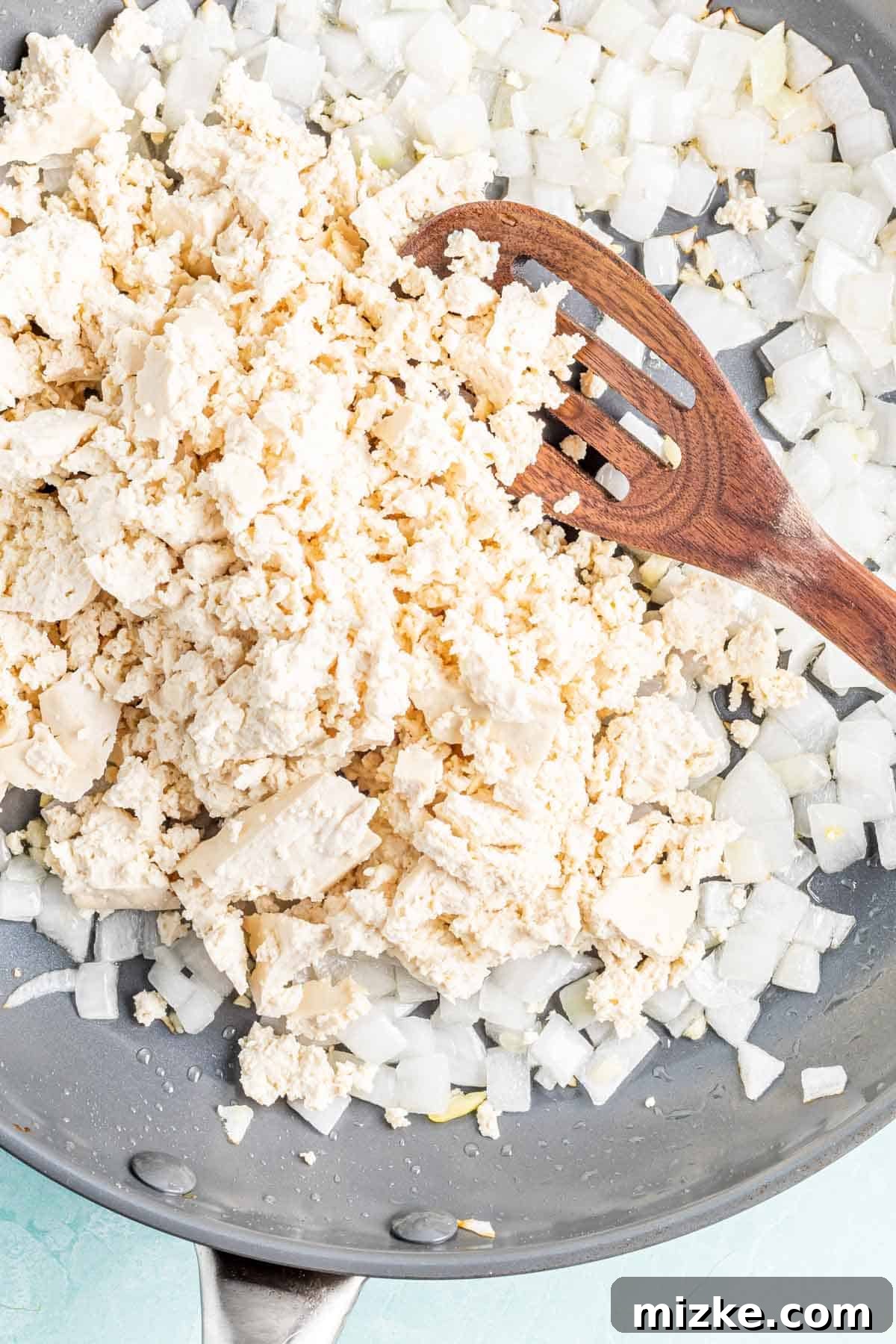 Spicy Tofu Chorizo 5 Crumbled tofu and sautéed onions mixing in a skillet with a wooden spoon.