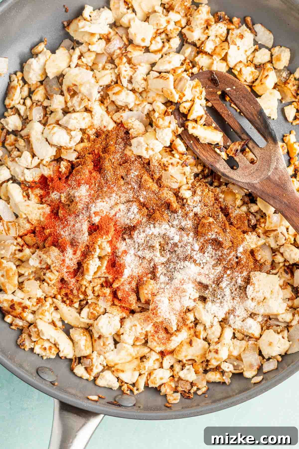 Spicy Tofu Chorizo 6 Tofu crumbles and onions in a skillet with a vibrant blend of dry spices added on top.