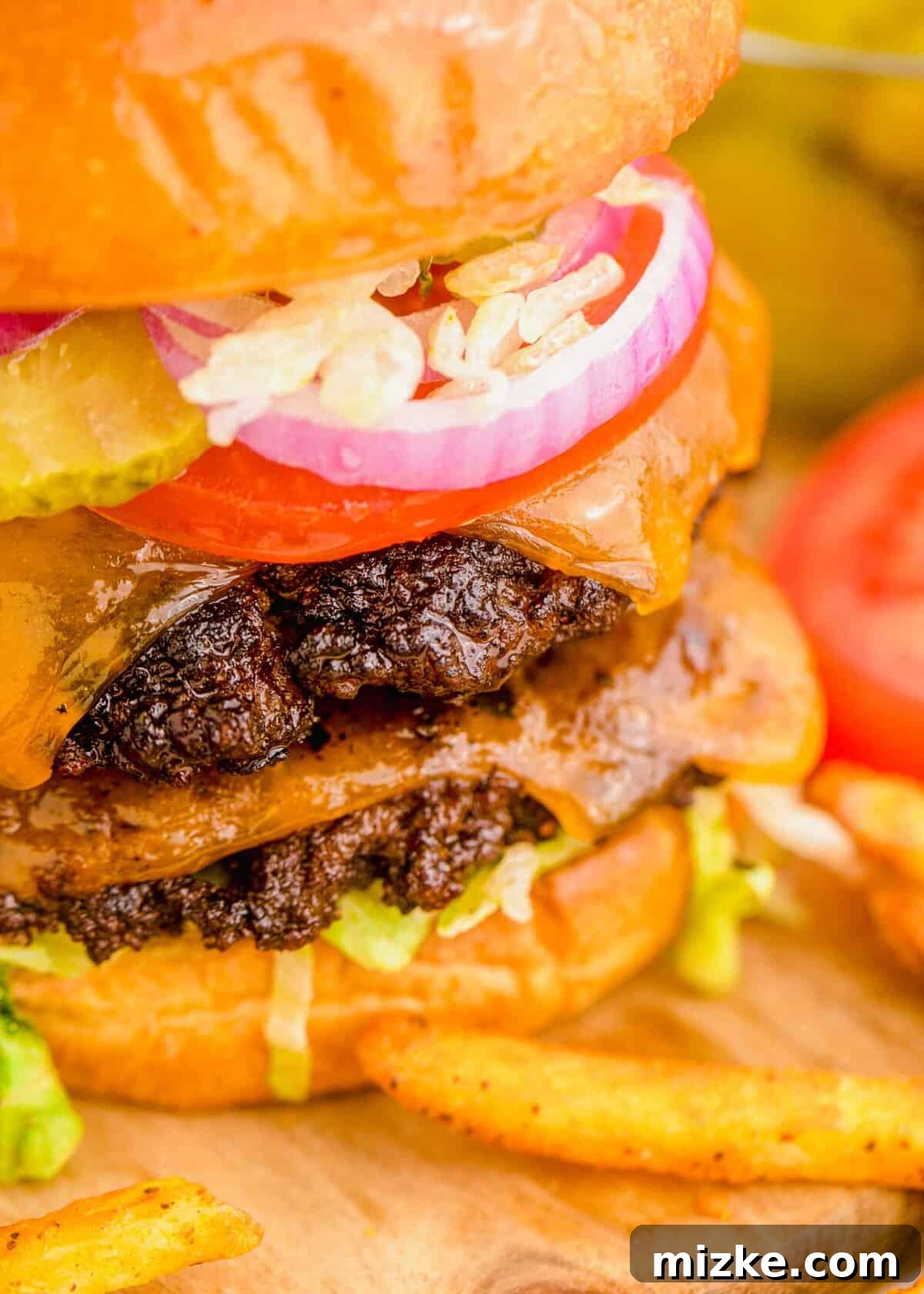 A stacked smash burger with two cheesy patties, fresh red onion, tomato slices, and crisp lettuce, nestled in a golden brioche bun, ready to be enjoyed.
