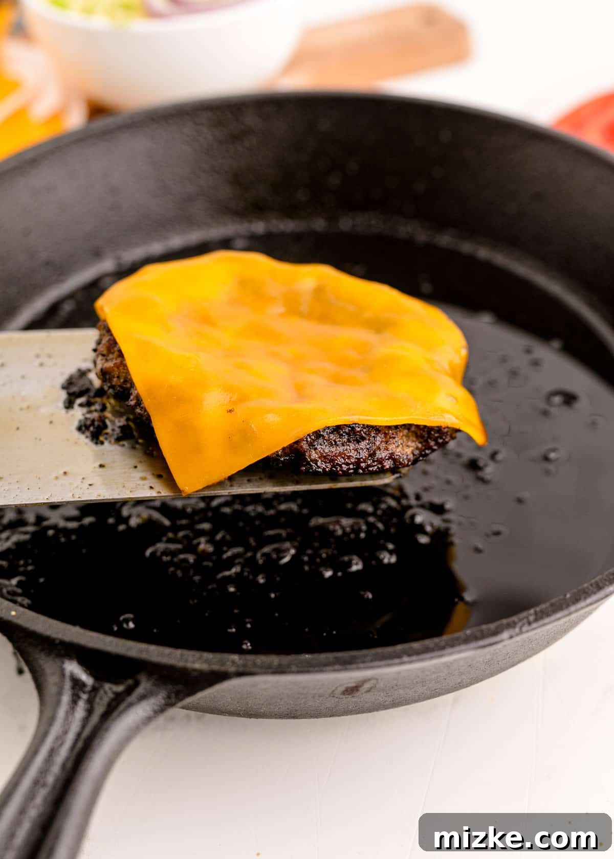 A slice of cheese just placed on a hot, freshly cooked ground beef patty, beginning to melt and soften.