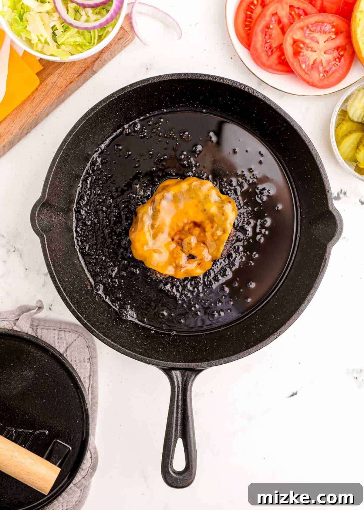 A slice of cheese fully melted and gooey over a hot smash burger patty, creating a luscious topping, ready for assembly.