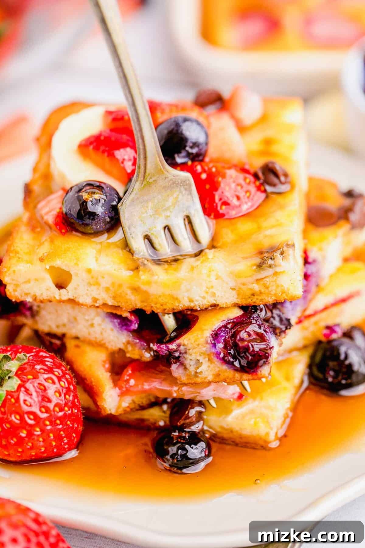 One-Pan Fruity Pancakes 14 A fork piercing a stack of golden sheet pan pancakes, ready for a delicious bite.