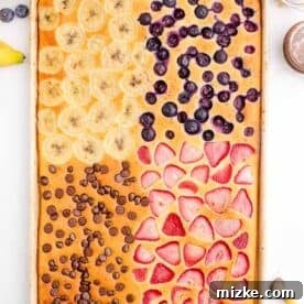 One-Pan Fruity Pancakes 21 A finished sheet pan fruit pancake, baked to a golden brown with visible fruit and chocolate chip toppings, ready for serving.