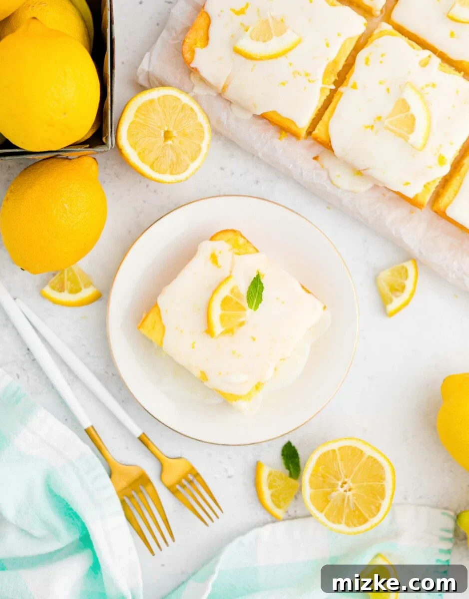 Lemon Bliss Sheet Cake 3 A perfectly square slice of moist lemon sheet cake, topped with smooth lemon icing, is elegantly presented on a classic round white plate, highlighting its inviting texture.