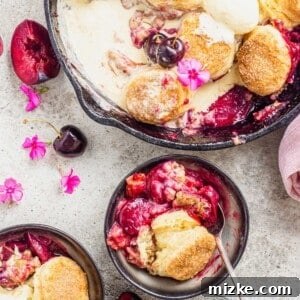 Biscuit-topped stone fruit cobbler in cast iron pan and two serving bowls