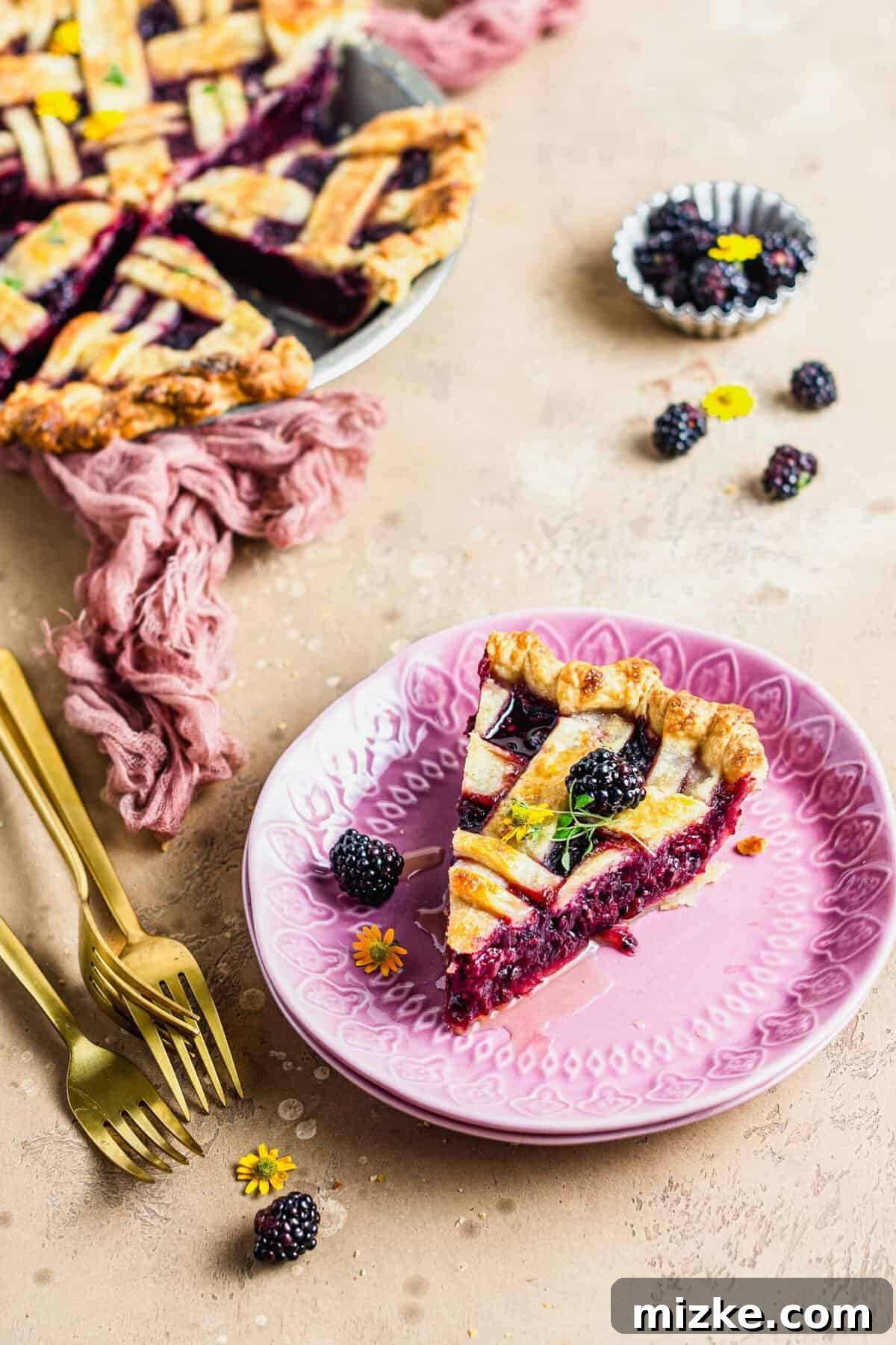 Thyme-Kissed Honey Blackberry Pie 3 A perfect slice of honey thyme blackberry pie on a plate, with the rest of the pie visible in the background.