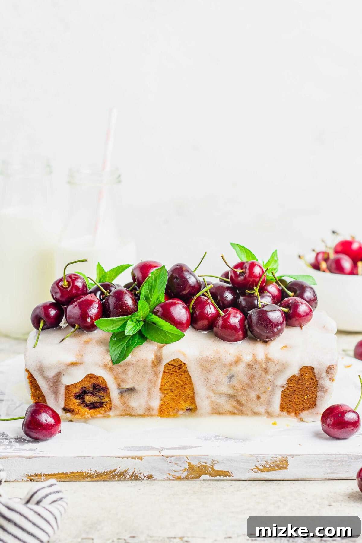 Velvet Cherry Amaretto Loaf 3 A stunning side view of the cherry amaretto loaf cake, elegantly garnished with fresh mixed berries and delicate mint leaves, ready for serving