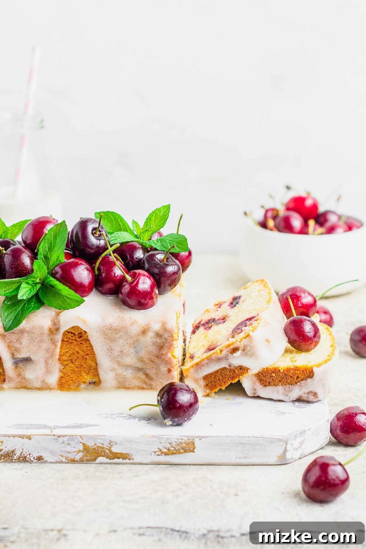 Velvet Cherry Amaretto Loaf 5 Cherry amaretto loaf cake garnished with fresh berries and mint, with two perfect slices cut and ready to serve