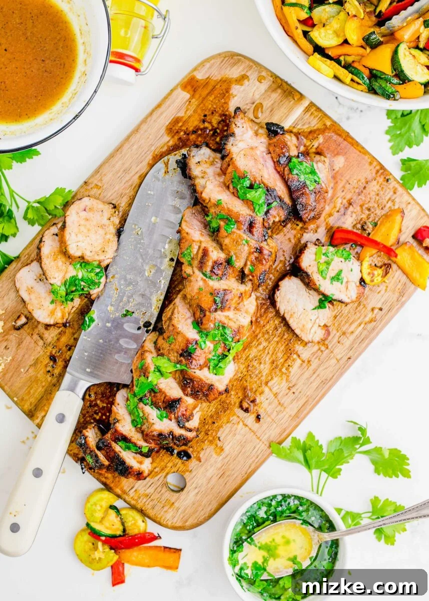 Succulent Grilled Pork Medallions 2 A grilled pork tenderloin has been sliced with a large knife on a wooden cutting board.