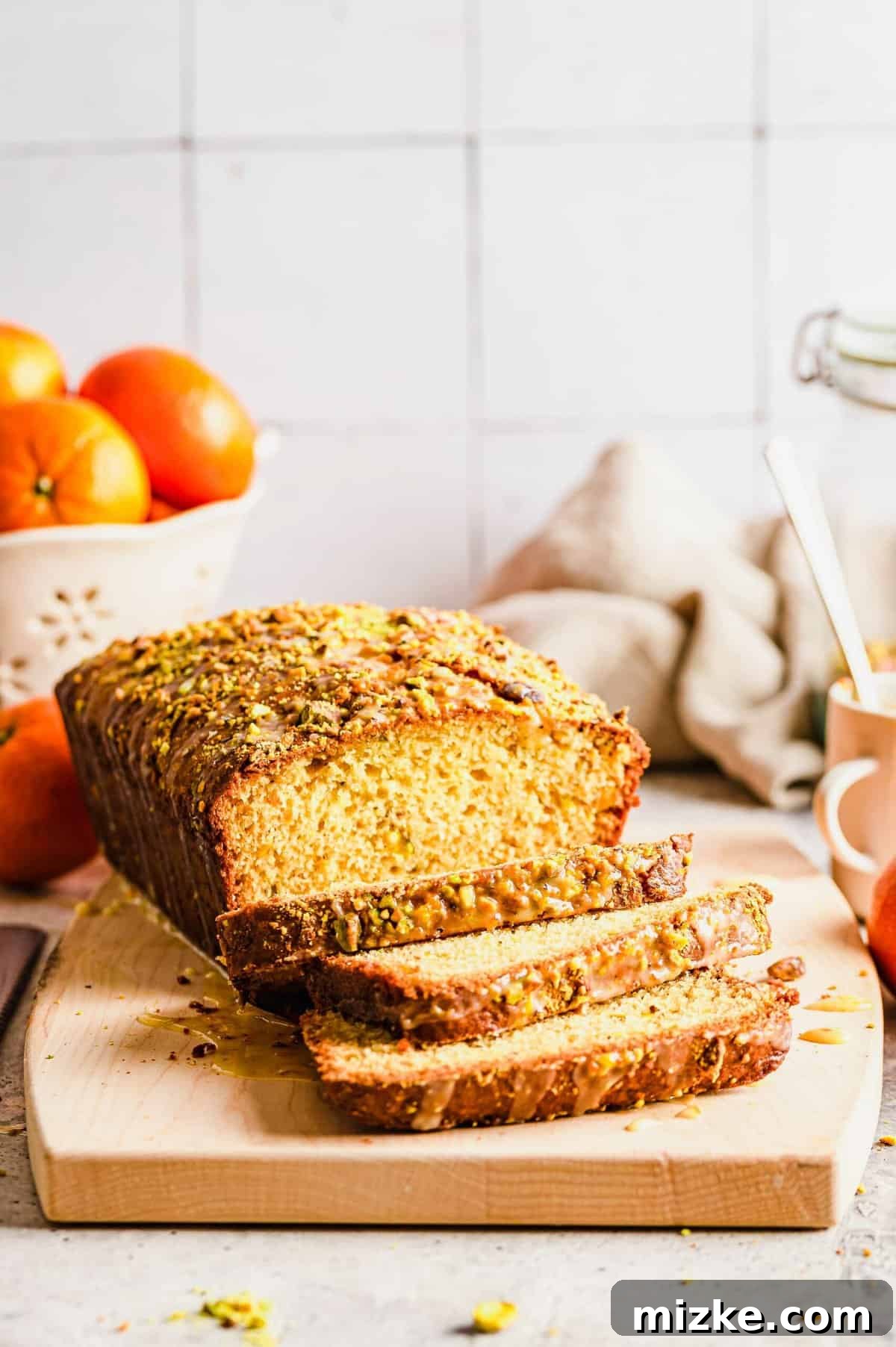 Zesty Orange Pistachio Loaf 5 Close-up of freshly glazed orange pistachio bread on a cooling rack, ready to be sliced.