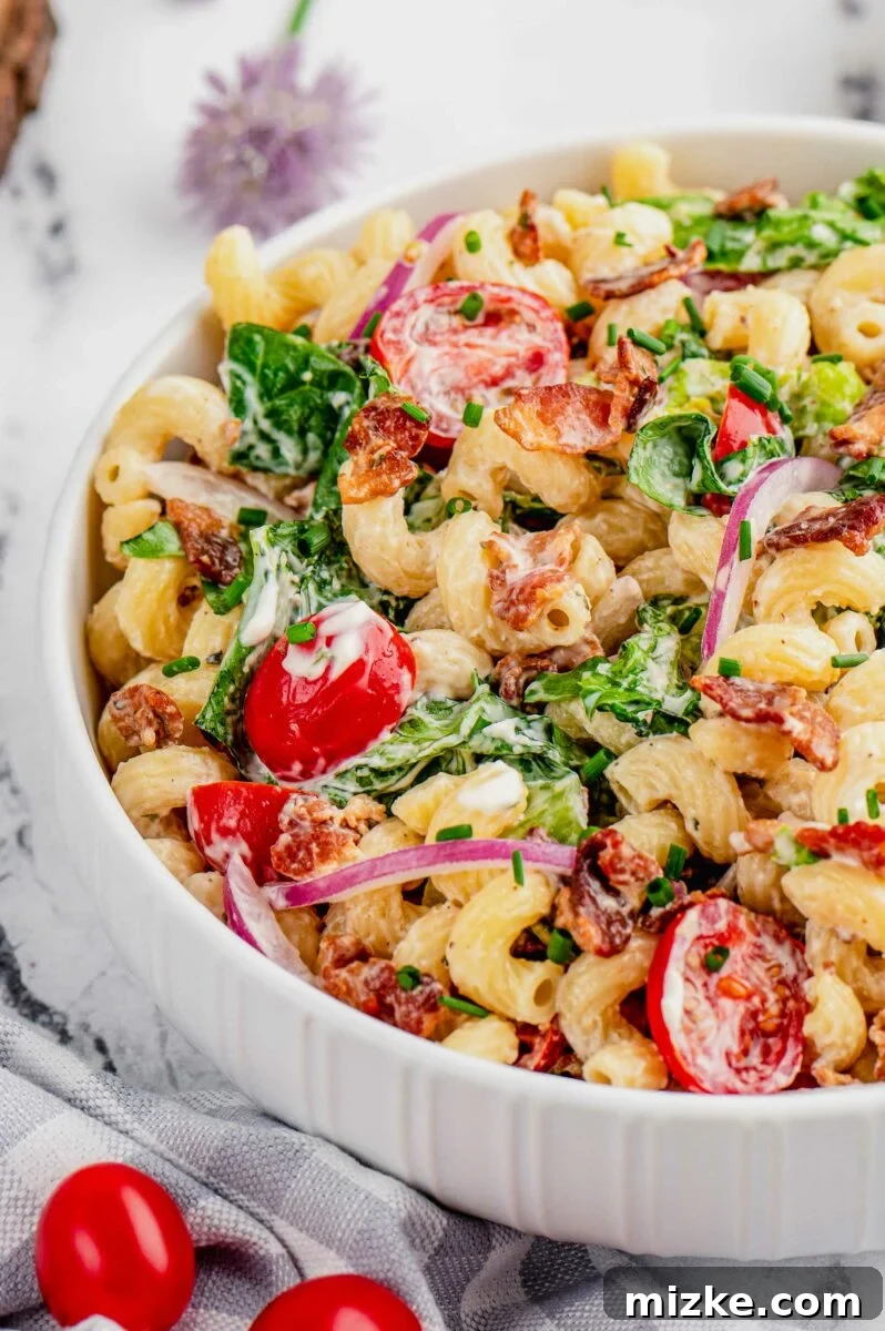 Savory BLT Pasta Medley 3 A close-up view of BLT pasta salad in a sleek white bowl, generously garnished with freshly chopped chives, showcasing the vibrant colors and creamy texture.