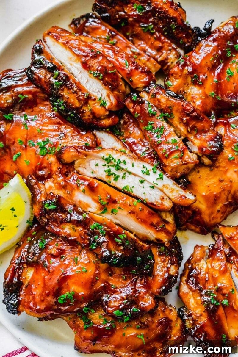 Classic Grilled BBQ Chicken 5 Grilling chicken thighs on an outdoor grill, with a brush applying BBQ sauce.
