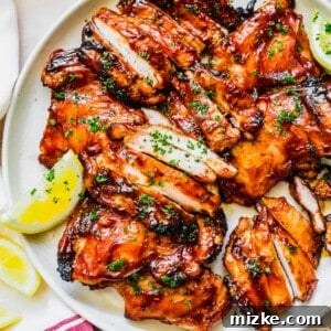 Grilled BBQ chicken thighs glazed with sauce, served with a side of corn.