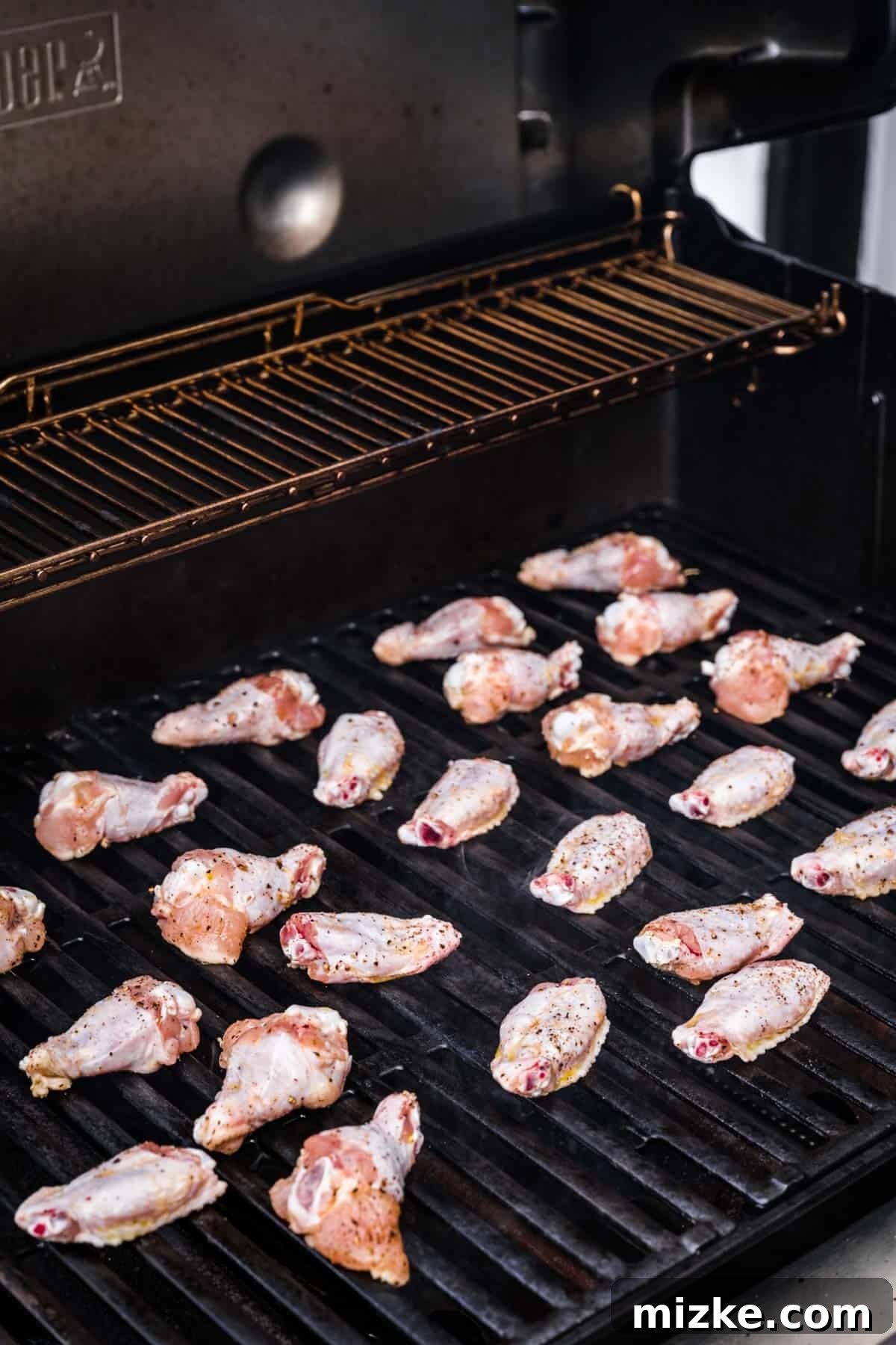 Irresistible Crispy Grilled Wings 5 Raw chicken wings neatly spaced out on the hot grates of an outdoor grill, ready for cooking to begin.