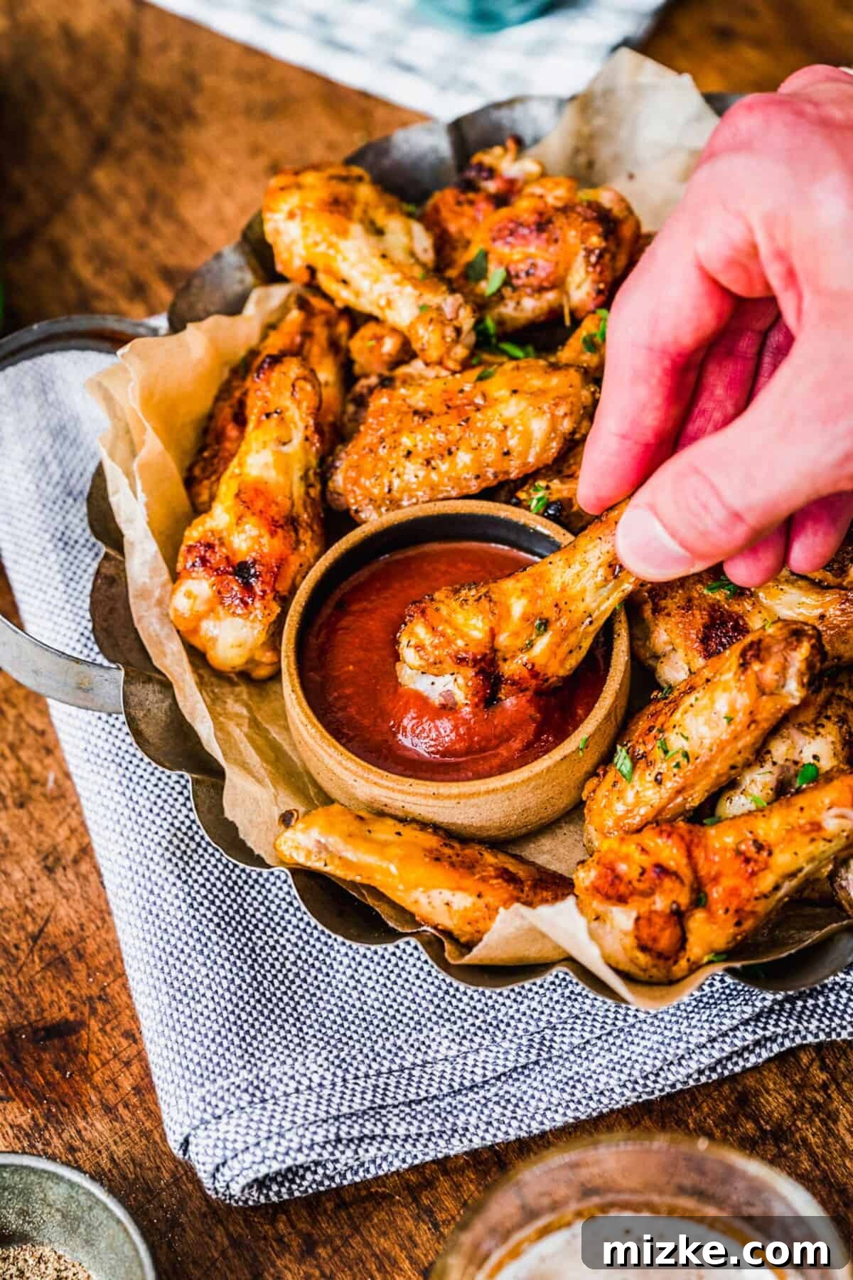 Irresistible Crispy Grilled Wings 9 A close-up shot of a perfectly grilled chicken drumstick being dipped into a rich, red sauce, showcasing its crispy skin and juicy interior.