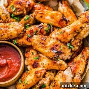 grilled chicken wings next to a red sauce and sliced cucumbers and carrots