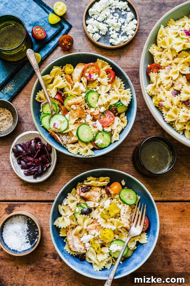 Zesty Greek Chicken Pasta Salad 4 Two individual servings of Greek Chicken Pasta Salad are presented in separate white bowls, ready to be enjoyed.