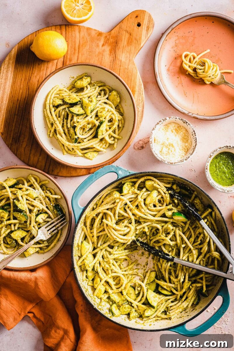 Velvety Lemon Zucchini Pasta 5 A generous serving of creamy zucchini lemon pasta in a large pot, with two individual portions plated alongside.