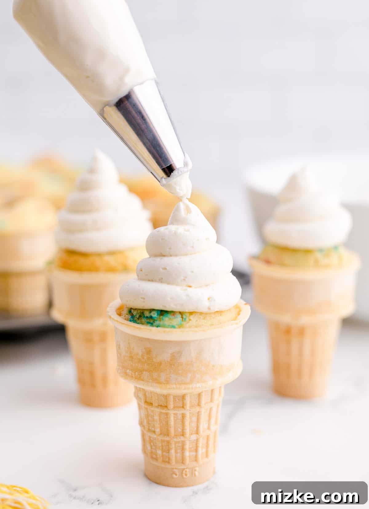 Waffle Cone Cupcakes 12 A beautiful swirl of vibrant buttercream is expertly piped onto the top of several ice cream cone cupcakes, showcasing the decorative frosting technique.