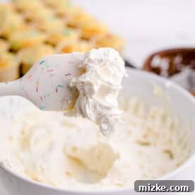 a white silicone spatula has buttercream frosting at the tip of it