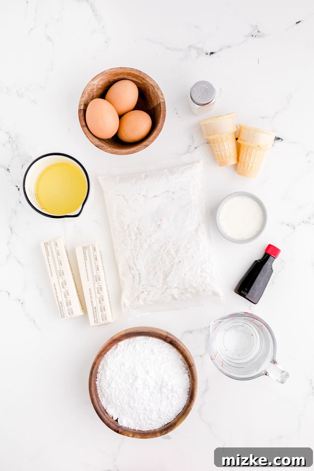 Waffle Cone Cupcakes 3 A flat lay photograph displaying all the fresh ingredients required for making ice cream cone cupcakes, including cake mix, cones, butter, and sugar.