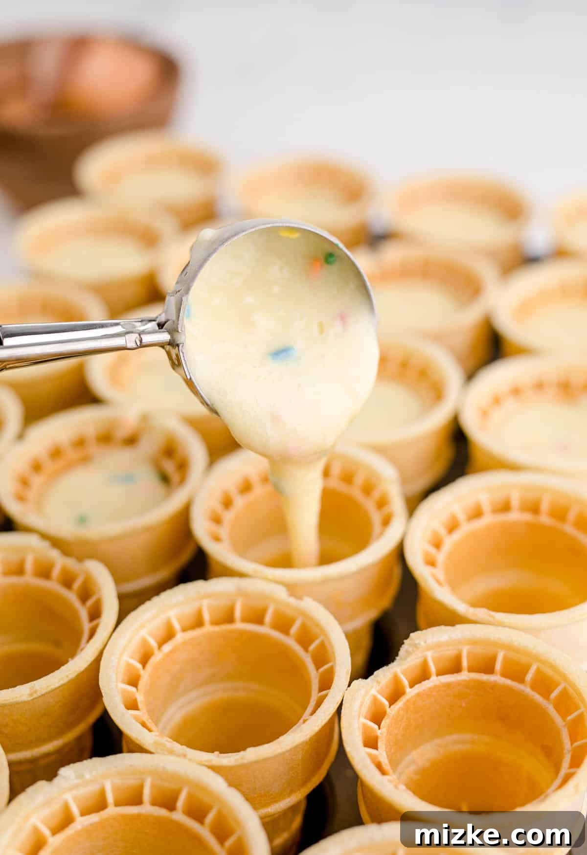 Waffle Cone Cupcakes 8 Using a cookie scoop to pour vibrant funfetti batter precisely into the empty ice cream cones, ensuring not to overfill.
