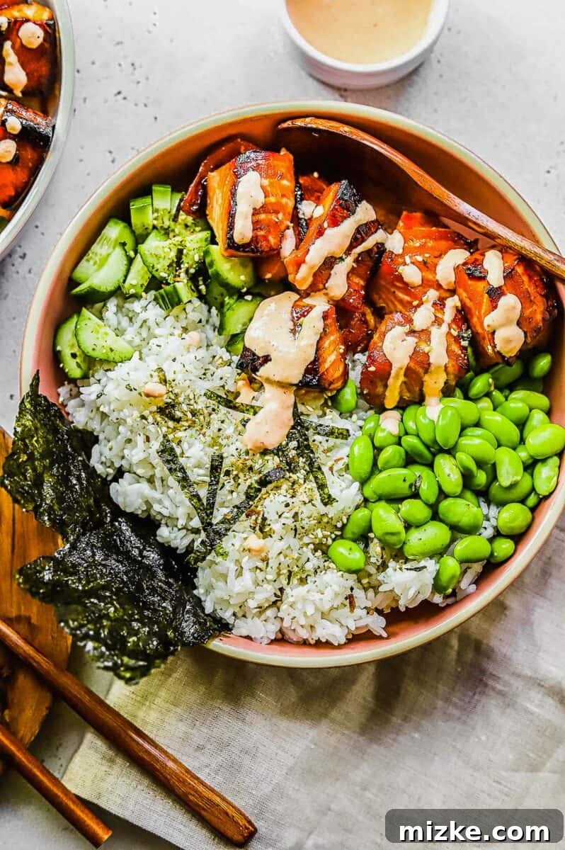 Effortless Salmon Rice Bowls 2 A bowl of salmon rice with seaweed, edamame, and cucumbers artistically arranged alongside the main dish.