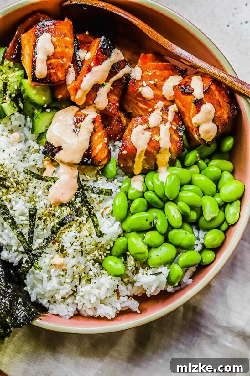 Effortless Salmon Rice Bowls 5 Spicy mayo being artfully drizzled over baked salmon cubes in a rice bowl.