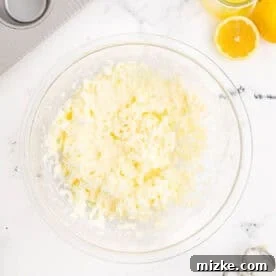 Creaming butter and sugar in a clear bowl with an electric mixer, creating a light and airy mixture.