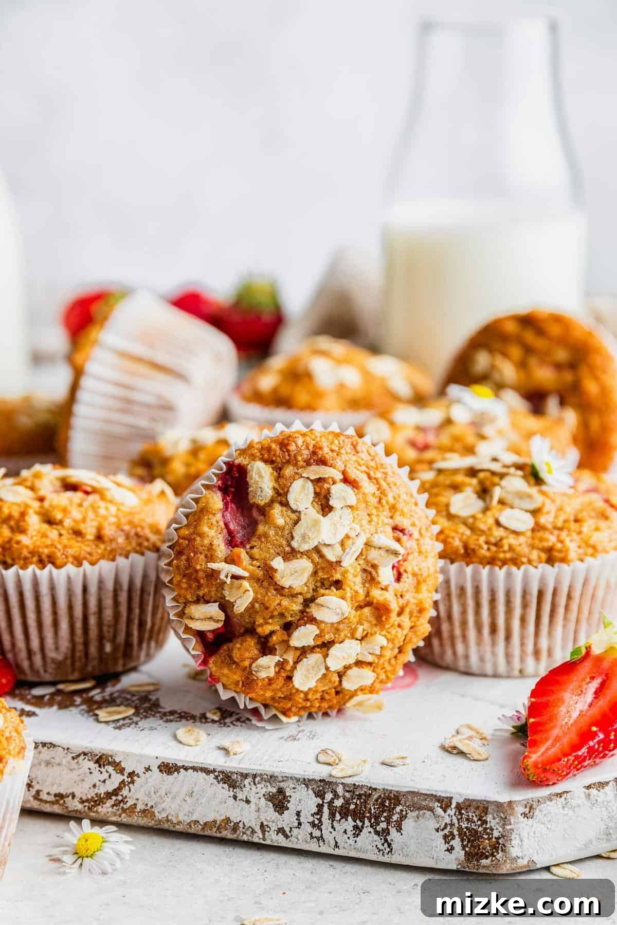 Sunrise Strawberry Oat Muffins 2 Freshly baked strawberry oatmeal muffins arranged on a rustic wooden board, ready for breakfast.