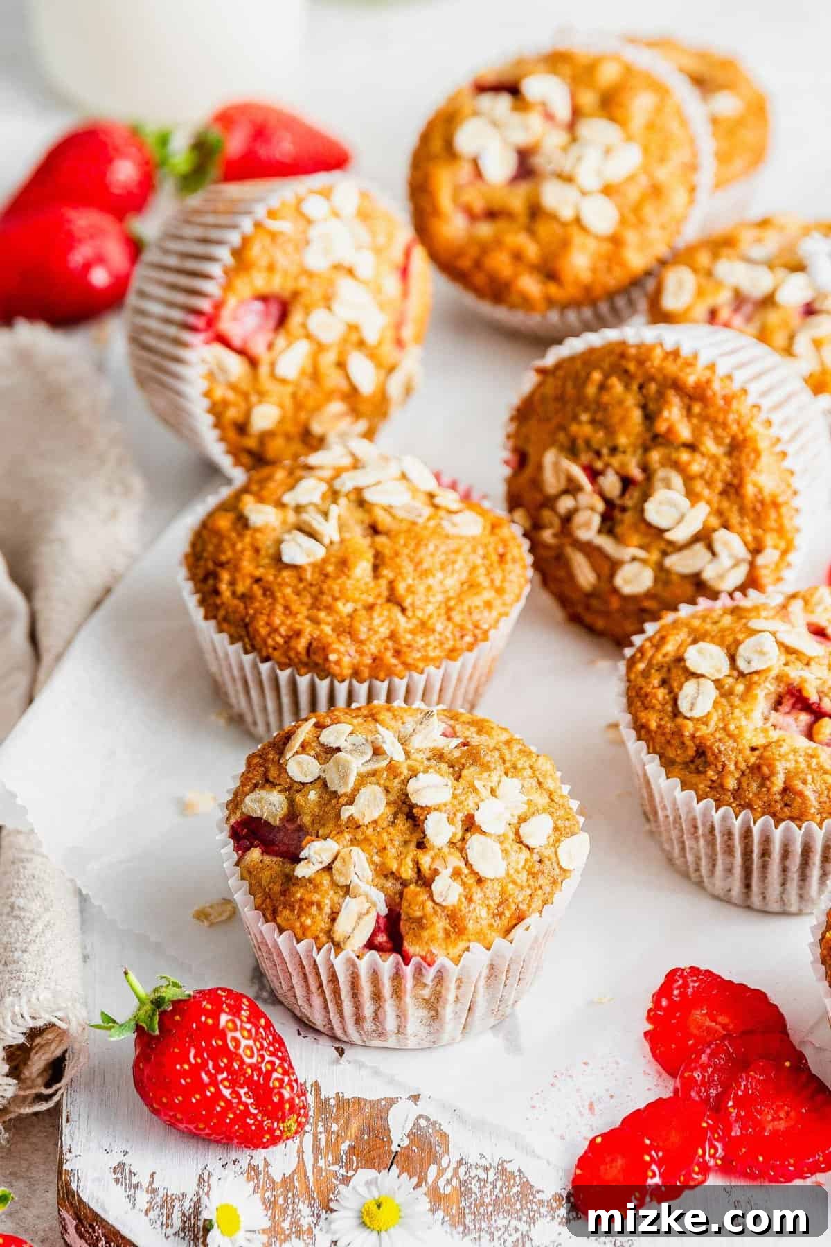 Sunrise Strawberry Oat Muffins 5 A batch of strawberry oatmeal breakfast muffins displayed artfully on a rustic wooden board.