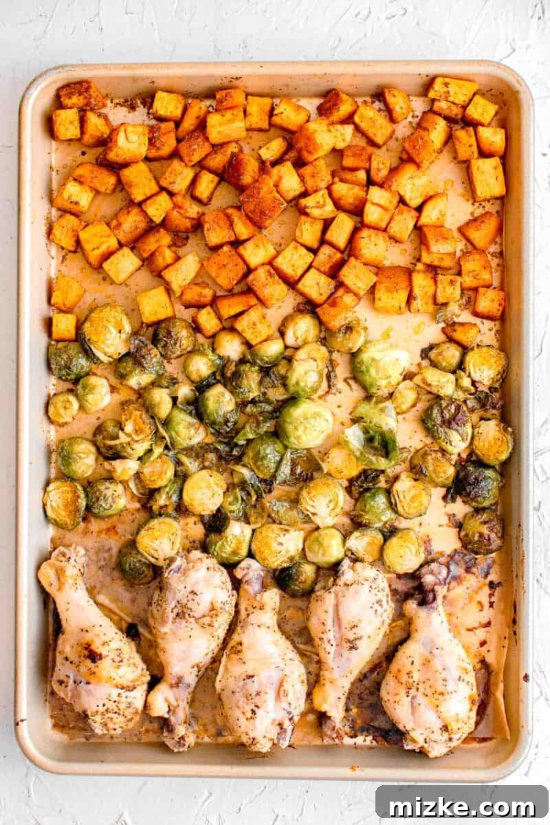 Zesty Golden Drumsticks 8 roasted sweet potatoes, brussels sprouts, and chicken legs on a rimmed baking sheet
