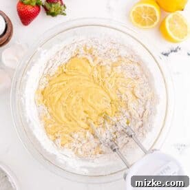 An electric mixer is mixing together cupcake batter in a clear bowl