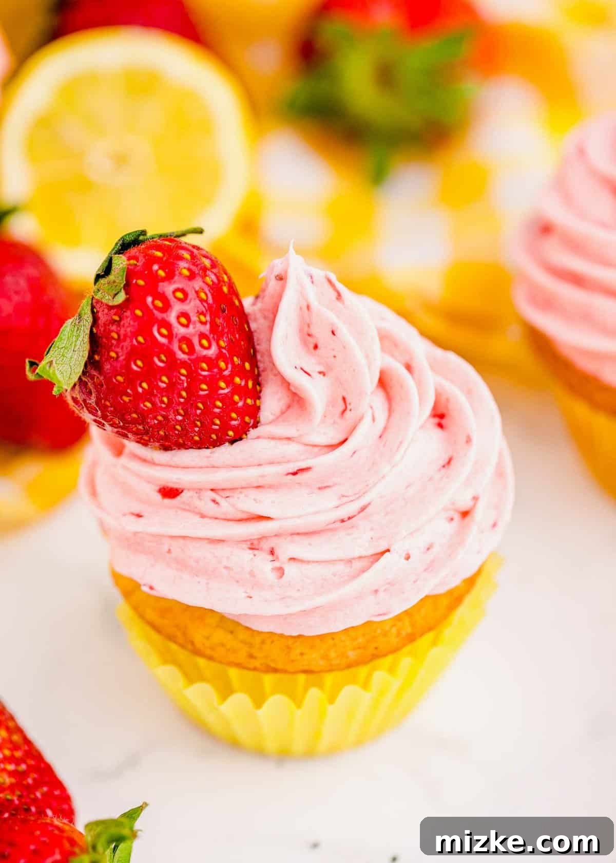 These Strawberry Lemonade Cupcakes achieve exceptional moistness and a fluffy buttercream thanks to simple yet effective ingredients. A single, perfectly frosted Strawberry Lemonade Cupcake, elegantly topped with a fresh strawberry slice, highlighting its vibrant colors and inviting texture.