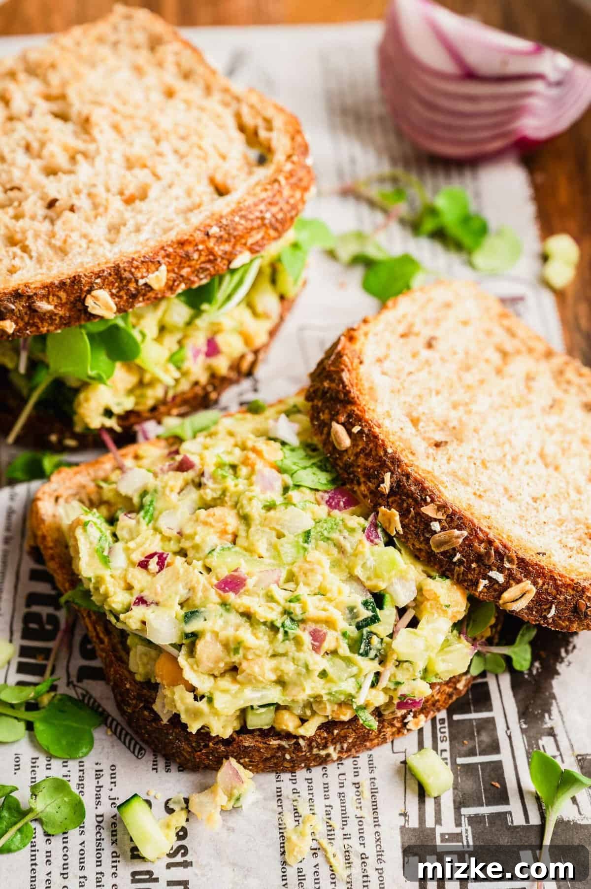 Smashed Chickpea Sandwich: Quick Vegan Recipe for Healthy Lunches Two vibrant smashed chickpea sandwiches, one cut open to reveal the rich, creamy, and colorful filling with fresh greens.