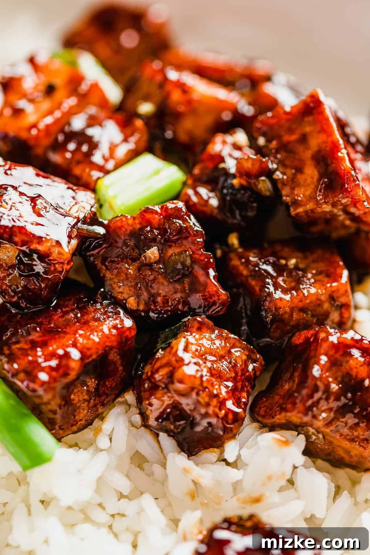 This black pepper tofu dish is a meatless entree that is sure to satisfy! The sauce has bold flavors that coat extra crispy tofu cubes! A vibrant bowl of black pepper tofu served over a bed of fluffy white rice, adorned with fresh green onions.