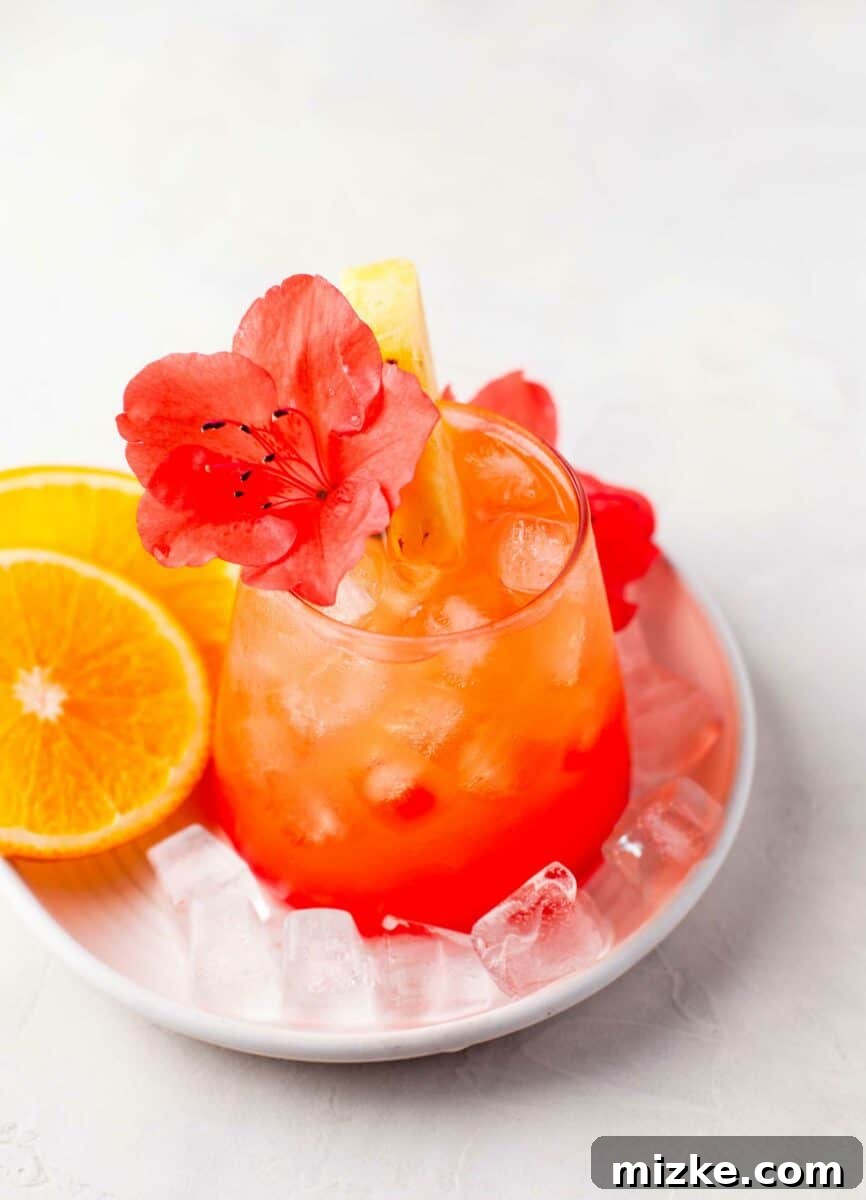 Sunshine Island Rum Punch 4 A garnished glass of Pineapple Orange Rum Punch surrounded by fresh orange slices, showcasing the vibrant colors and appealing presentation.