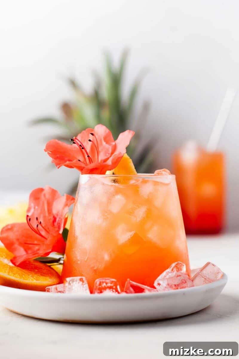 Sunshine Island Rum Punch 5 A glass of Pineapple Orange Rum Punch artfully presented with fresh flowers around and on top, emphasizing its celebratory and beautiful nature.