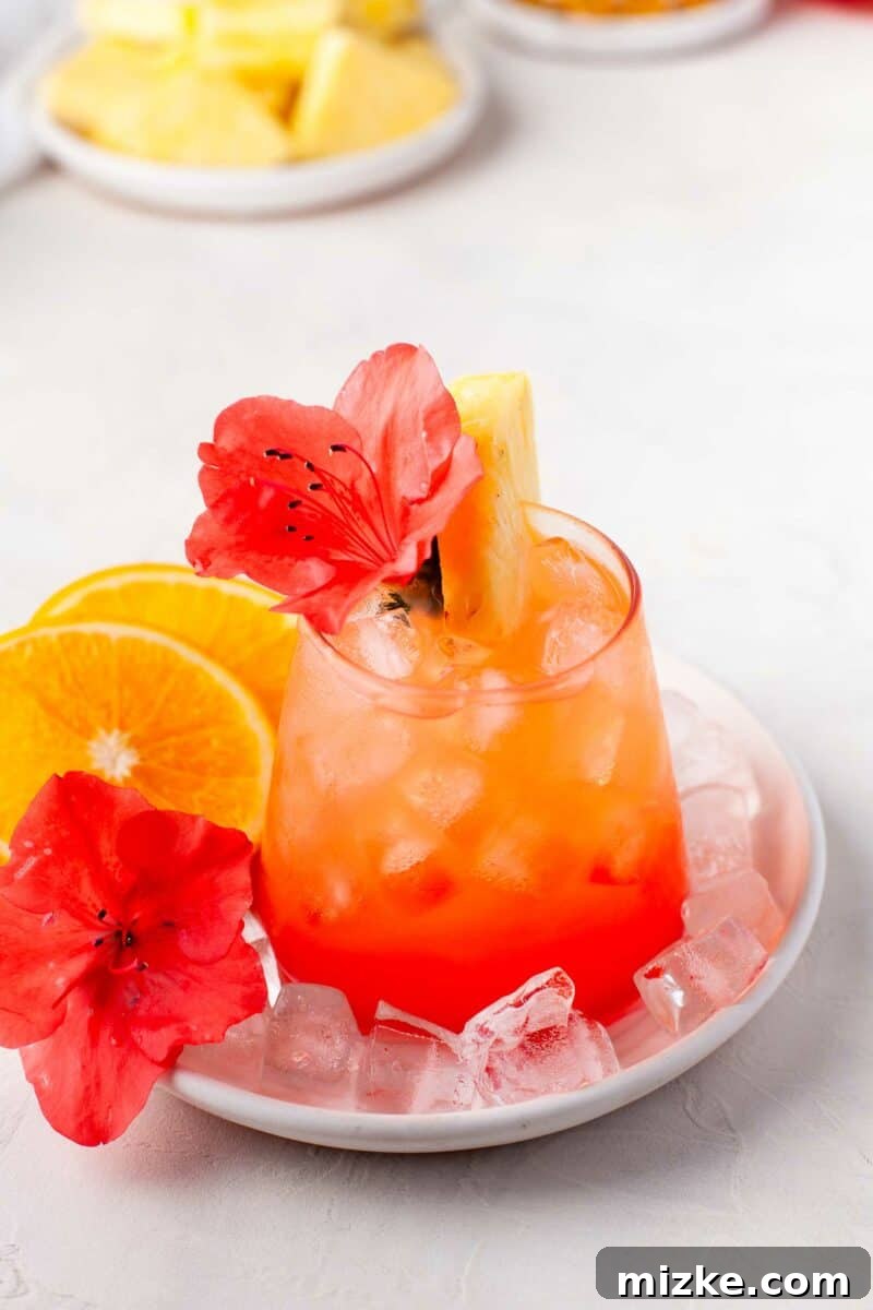 Sunshine Island Rum Punch 6 A perfectly mixed glass of Pineapple Orange Rum Punch presented on a minimalist round white plate with scattered ice cubes, ready to be enjoyed.