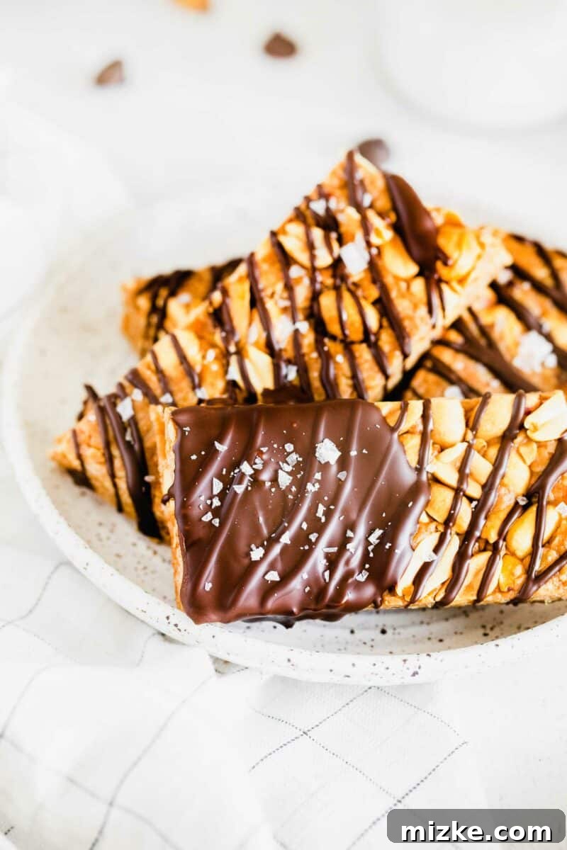 Chocolate Peanut Power Bars 3 A single homemade granola bar, beautifully dipped and drizzled with melted chocolate, is sprinkled with flaky sea salt, highlighting its delicious finish.