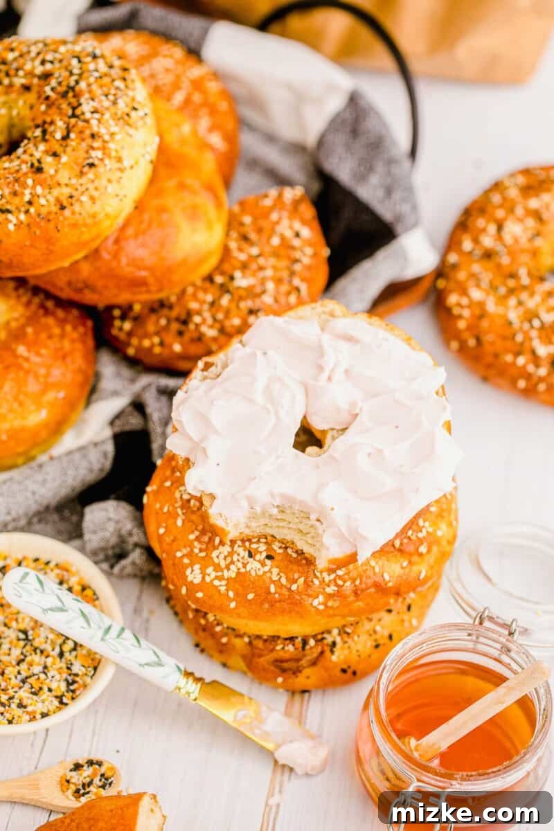 Chewy Homemade Bagels From Scratch 18 A freshly baked bagel, halved and generously topped with smooth cream cheese, ready to be enjoyed.